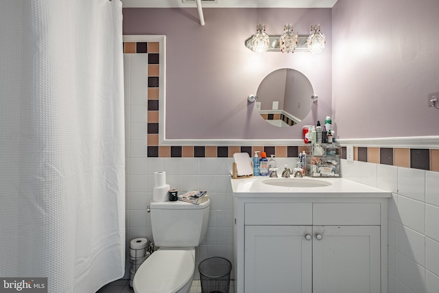 full bath with toilet, a shower with shower curtain, visible vents, vanity, and tile walls