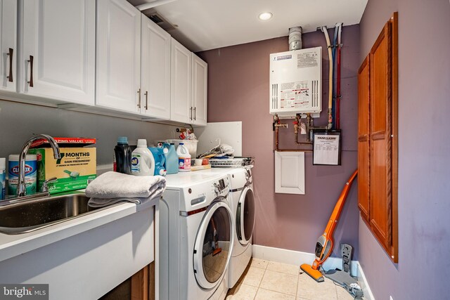 clothes washing area with tankless water heater, washer and dryer, sink, light tile patterned flooring, and cabinets