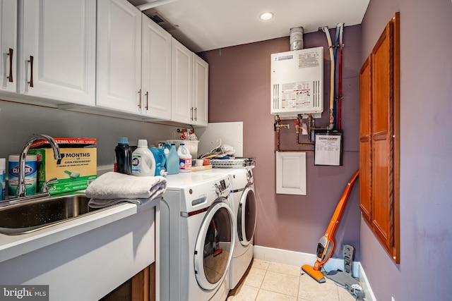 clothes washing area with light tile patterned floors, a sink, water heater, cabinet space, and washing machine and clothes dryer