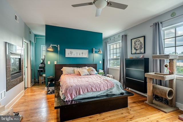 bedroom with wood-type flooring, visible vents, ceiling fan, and baseboards