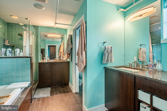 full bath featuring wood finish floors, a stall shower, vanity, baseboards, and a bath