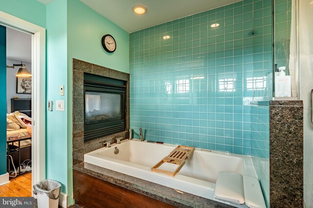 bathroom featuring tile walls, a bathtub, and hardwood / wood-style flooring