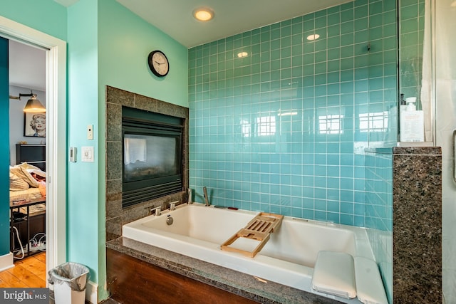 full bath with a bath, a tiled fireplace, and tile walls