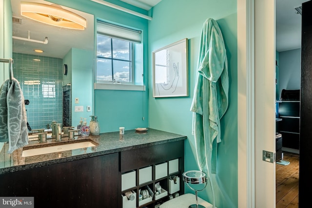 bathroom featuring visible vents, tiled shower, vanity, and wood finished floors