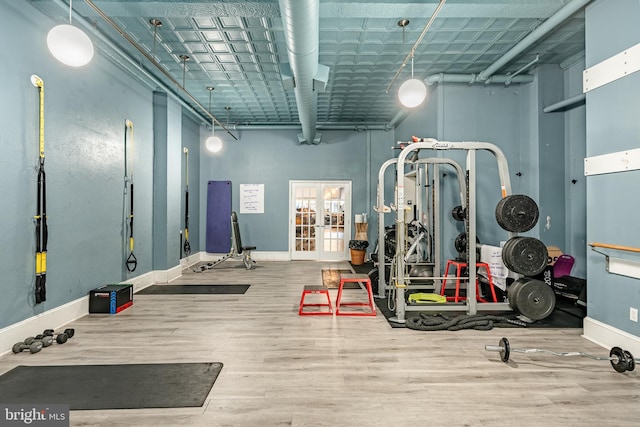 exercise room with a towering ceiling, baseboards, and wood finished floors