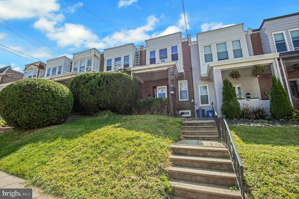 townhome / multi-family property with a residential view, brick siding, and a front lawn