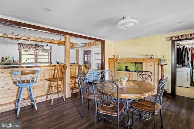 dining space featuring washer / clothes dryer, dark wood-type flooring, and bar area