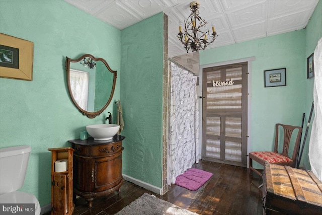 bathroom with toilet, hardwood / wood-style flooring, a notable chandelier, and vanity