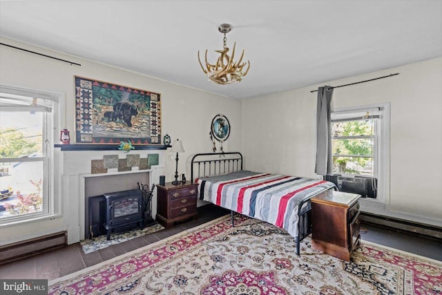 bedroom with hardwood / wood-style floors, a baseboard radiator, a wood stove, and cooling unit