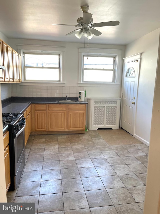 kitchen with ceiling fan, light tile patterned floors, radiator heating unit, black range with gas cooktop, and decorative backsplash