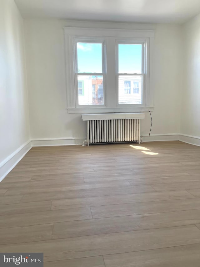 empty room with light wood-type flooring and radiator