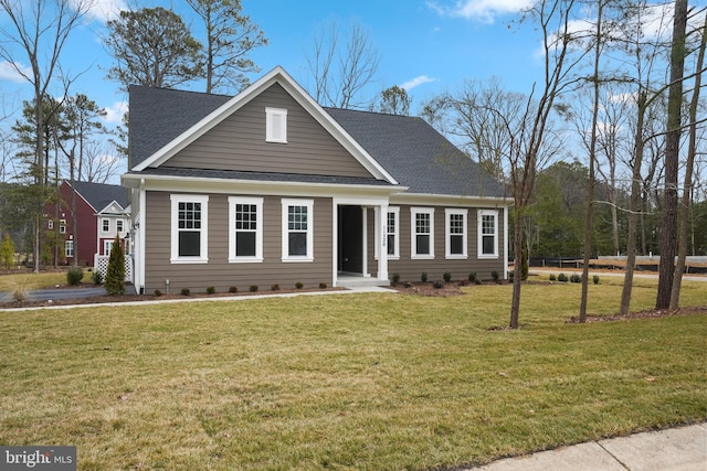 view of front facade with a shingled roof and a front lawn