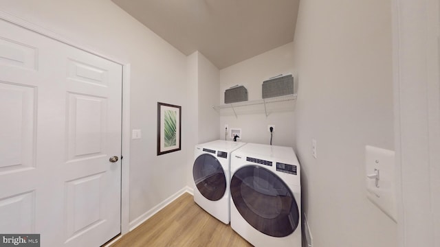 clothes washing area with laundry area, baseboards, light wood finished floors, and washer and dryer