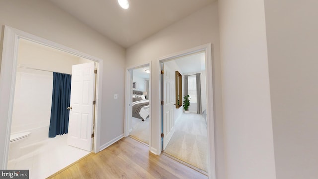 hallway featuring light wood-type flooring and baseboards