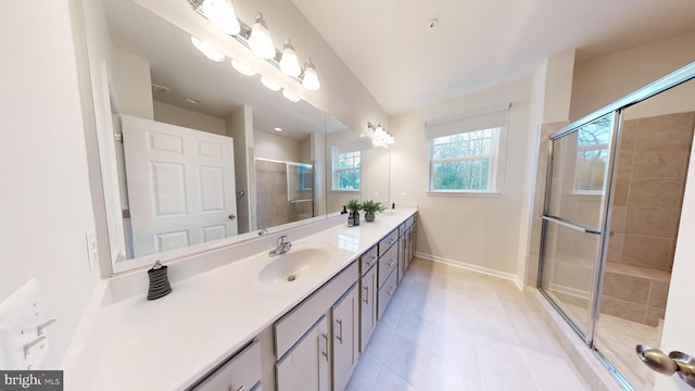 bathroom featuring a sink, baseboards, tile patterned floors, double vanity, and a stall shower