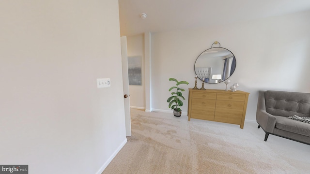 living area featuring light carpet and baseboards