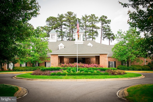 view of front of property featuring a shingled roof and brick siding