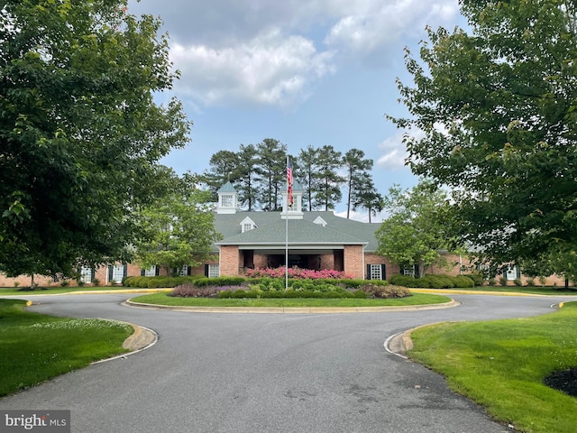 view of front of home with a front yard, brick siding, and driveway