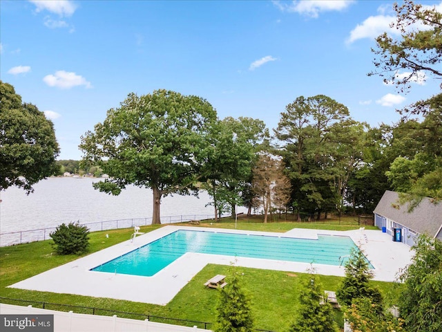 community pool featuring a water view, a patio area, fence, and a lawn