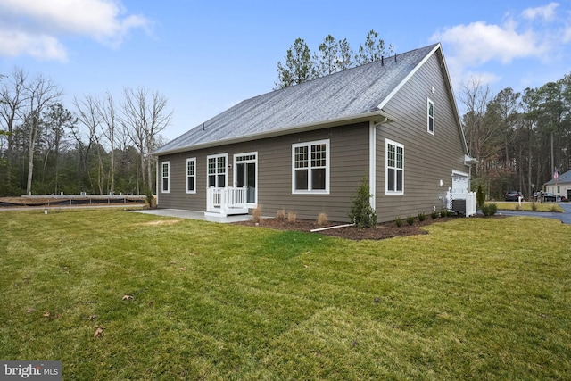 rear view of property featuring a garage, a yard, and central air condition unit