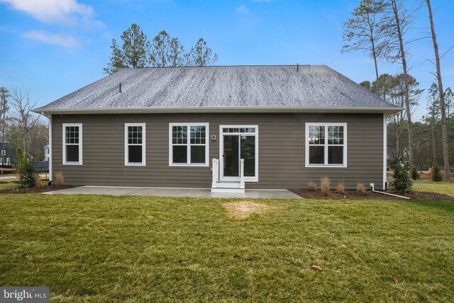 rear view of house with a yard, roof with shingles, and a patio