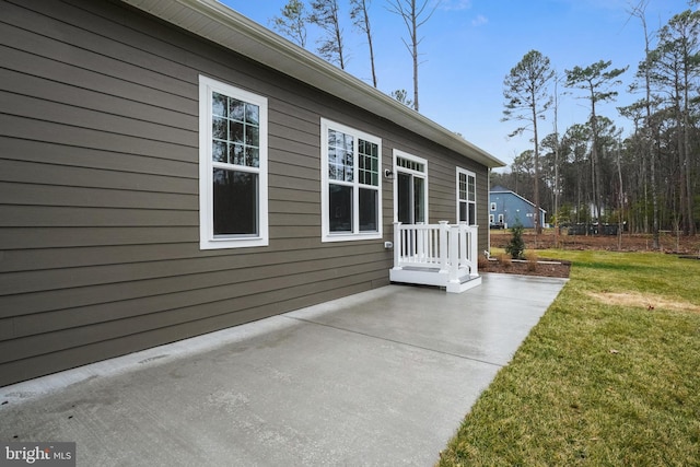 view of side of property featuring a patio and a lawn