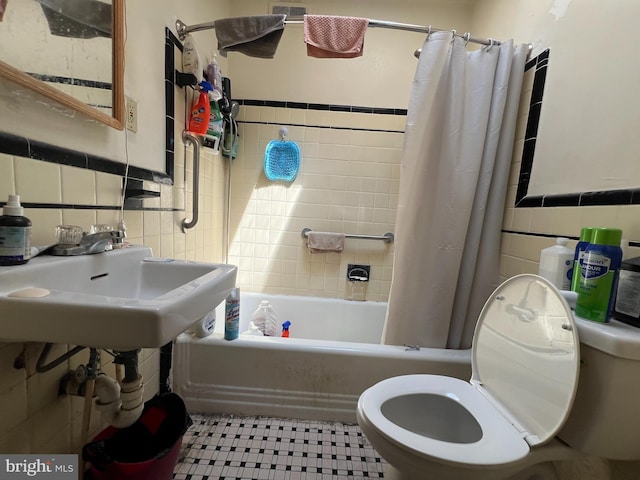 bathroom featuring tile walls, toilet, and shower / bathtub combination with curtain