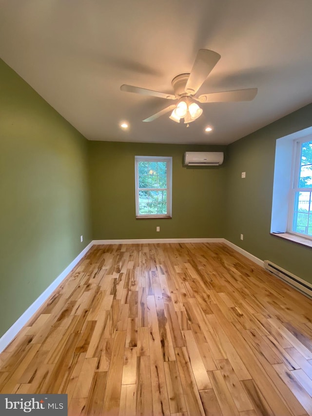 spare room with a wall mounted AC, ceiling fan, a baseboard radiator, and light hardwood / wood-style floors