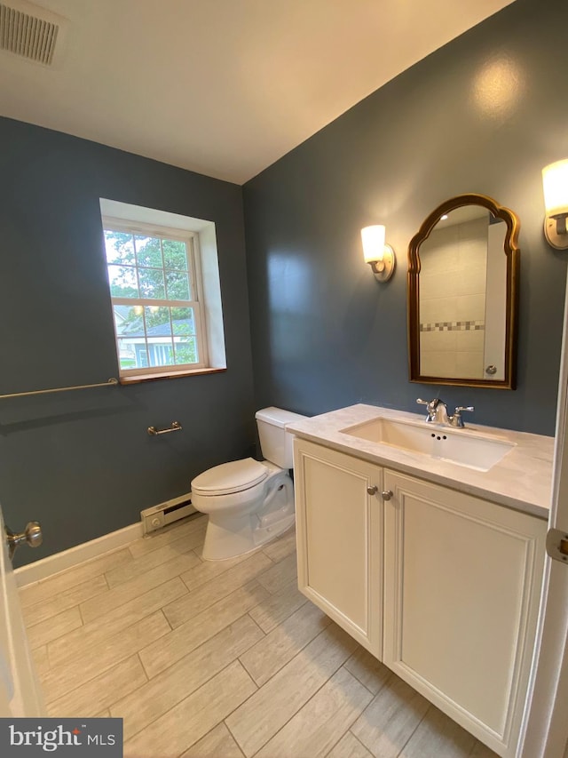 bathroom featuring a baseboard radiator, toilet, hardwood / wood-style flooring, and vanity