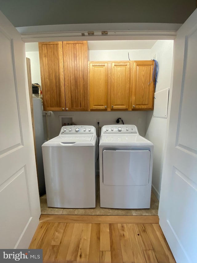 laundry room featuring light wood-type flooring, independent washer and dryer, and cabinets