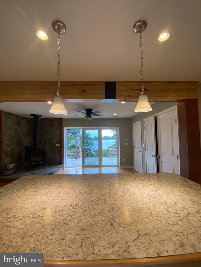 interior space featuring ceiling fan, a wood stove, and hanging light fixtures