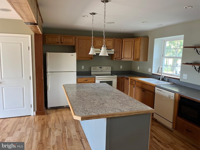 kitchen with white appliances, a center island, sink, and light hardwood / wood-style floors