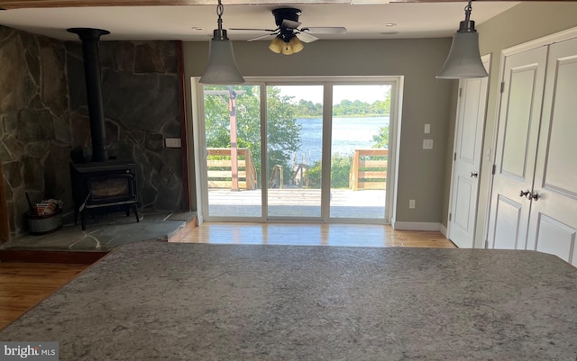 unfurnished living room with a wood stove, ceiling fan, and hardwood / wood-style flooring