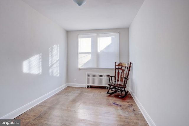 sitting room with baseboards, light wood-style flooring, and radiator heating unit