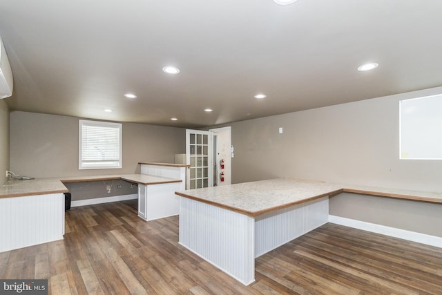 kitchen with dark wood-type flooring, white cabinets, a center island, and kitchen peninsula