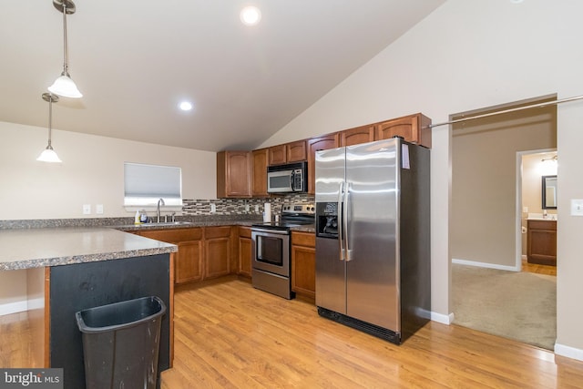 kitchen featuring light wood-type flooring, pendant lighting, stainless steel appliances, kitchen peninsula, and sink