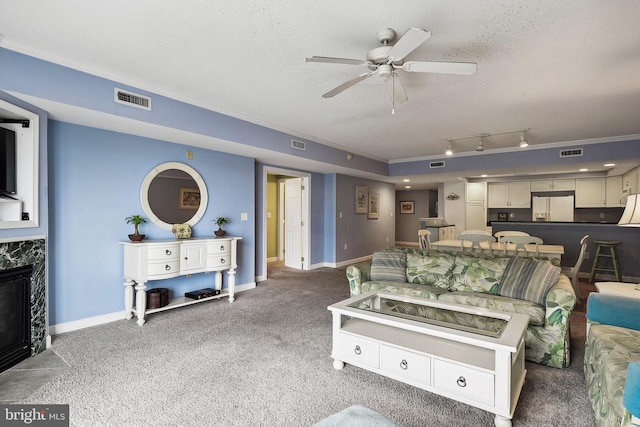 carpeted living room featuring ornamental molding, a textured ceiling, a high end fireplace, and ceiling fan