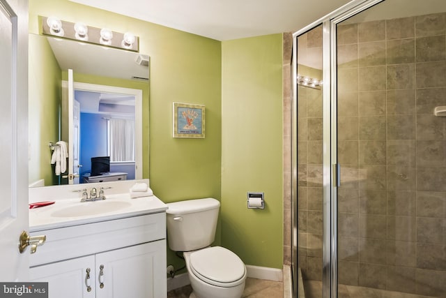 bathroom featuring toilet, vanity, tile patterned flooring, and a shower with shower door