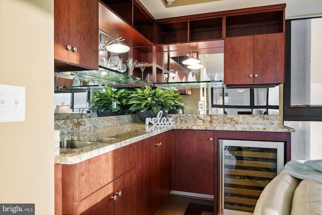 kitchen featuring light stone counters, wood-type flooring, and beverage cooler