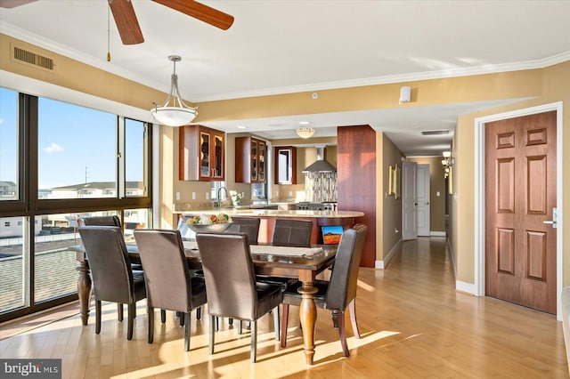 dining space with crown molding, light hardwood / wood-style floors, and ceiling fan