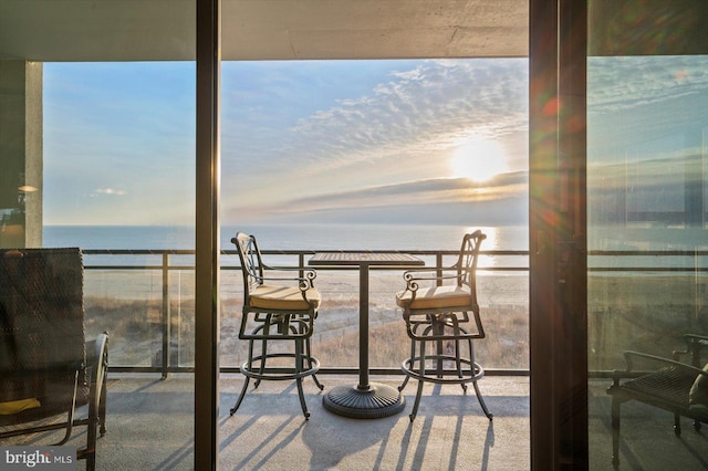 balcony at dusk featuring a water view