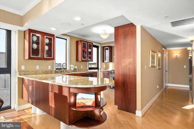 kitchen featuring light stone counters, ornamental molding, kitchen peninsula, and light hardwood / wood-style floors