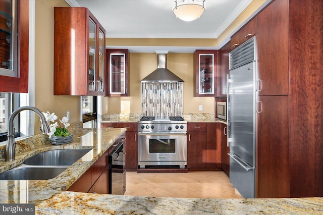 kitchen featuring sink, crown molding, wall chimney range hood, high end appliances, and light stone countertops