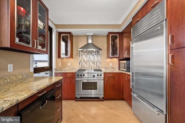 kitchen featuring premium appliances, crown molding, light stone countertops, and wall chimney exhaust hood