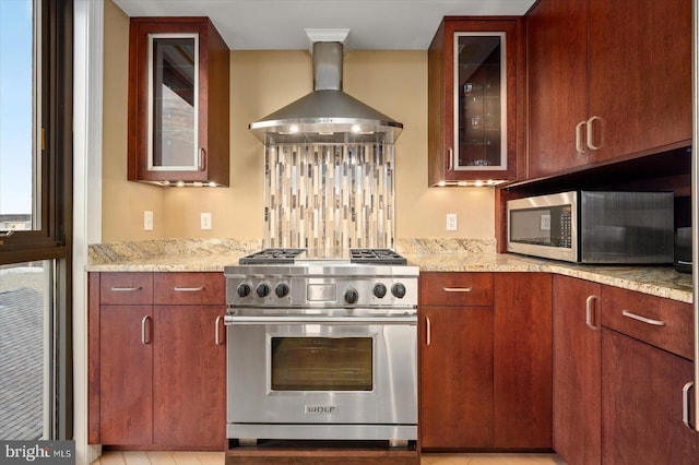 kitchen with light stone counters, appliances with stainless steel finishes, wall chimney exhaust hood, and backsplash