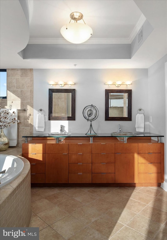 bathroom with tile patterned flooring, vanity, a relaxing tiled tub, a tray ceiling, and ornamental molding