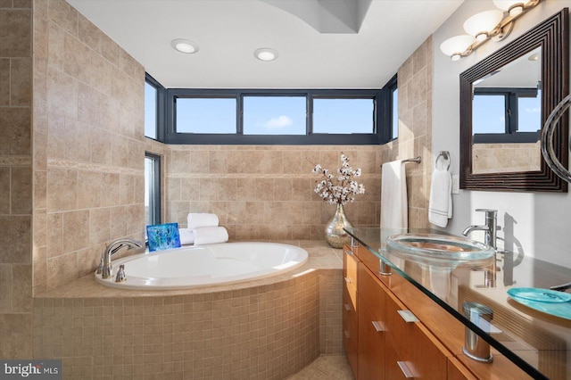 bathroom with plenty of natural light, vanity, tile walls, and tiled tub