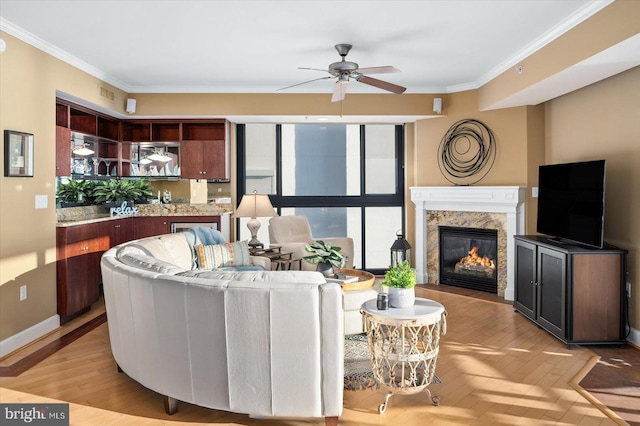 living room with crown molding, ceiling fan, a fireplace, and light hardwood / wood-style floors