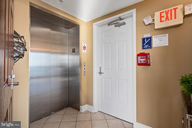 hall featuring light tile patterned floors and elevator