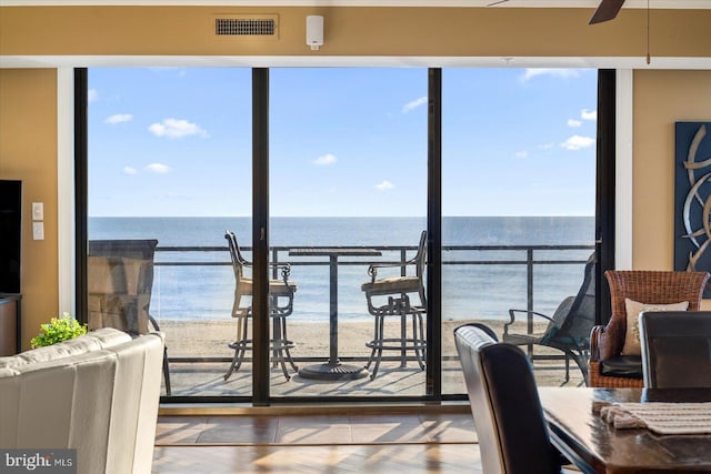 interior space with ceiling fan, a beach view, and a water view